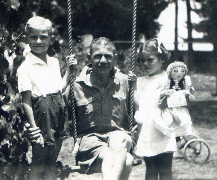 Junior’s dad on ‘The Swing’ . Junior to the left and Elizabeth Withall to the right with the Polly Doll made by Junior’s mum.