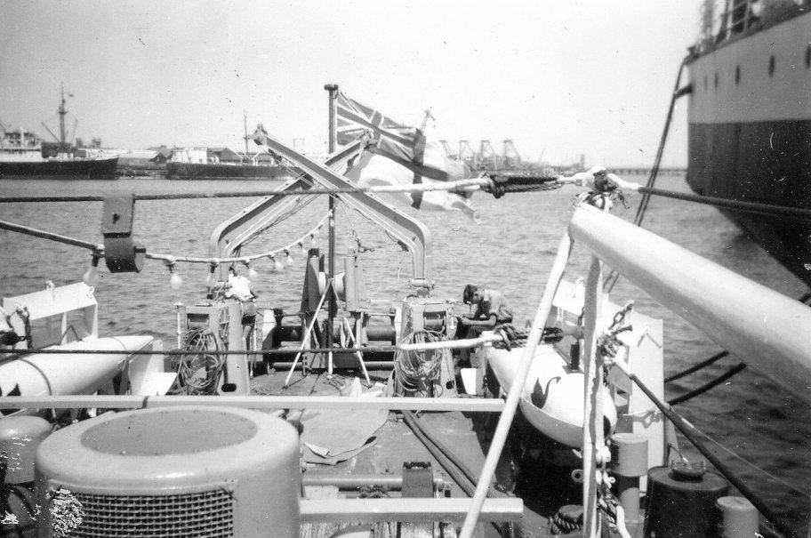 Quarterdeck of HMAS Fremantle (Note ora-pisa paravanes on either side of quarterdeck and depth-charge equipment at stern. Fremantle is tied up alongside a Blue Funnel cargo ship in Fremantle Harbour)