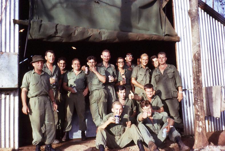 Celebration on completion of our first tropical work hut. Left to right –Snow Rollston, Dave Christie, HQ Q pers, Stan Johns, Ken Slater, Bob Skitch, L/Bdr Sellwood, Dennis Duquemin, 131 Loc Bty svyr, Pte Renzo US Bty svyr, S/Sgt Glascow US…